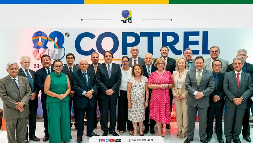 Foto colorida, com dezesseis homens e cinco mulheres, posando para foto em pé e sorridentes. Atr...
