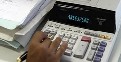 Pessoa fazendo contas em calculadora de mesa